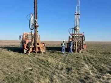 Two Anchor King anchor trucks with masts raised on an Alberta lease