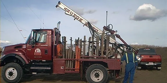 Anchor King truck racked with anchors, auger boom extended