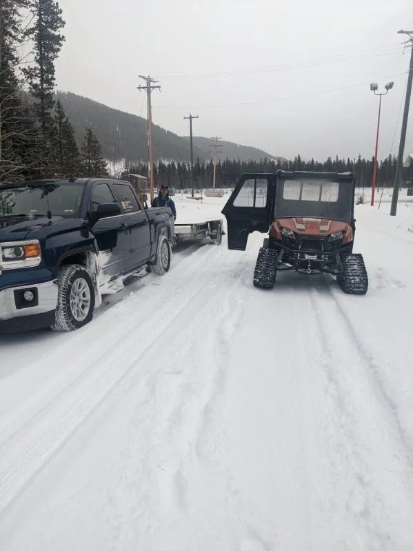 Pickup truck and tracked utility vehicle on a snowed-in road